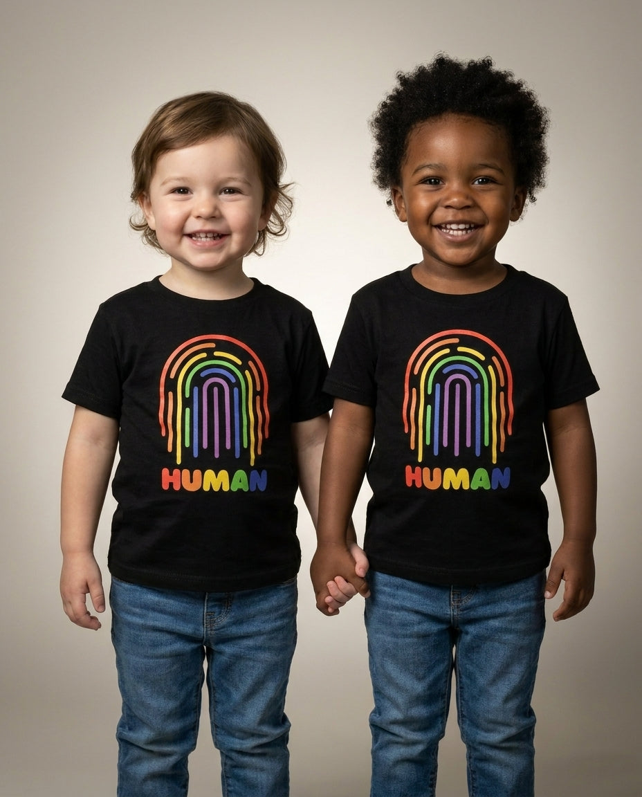 Two toddlers holding hands in the HUMAN Pride toddler tee