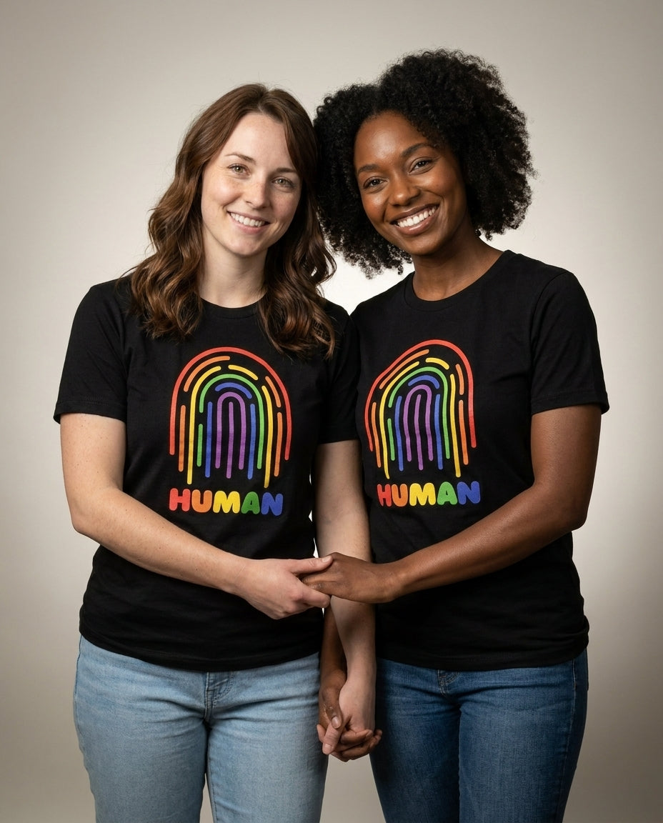 Two women holding hands in the HUMAN Pride tee