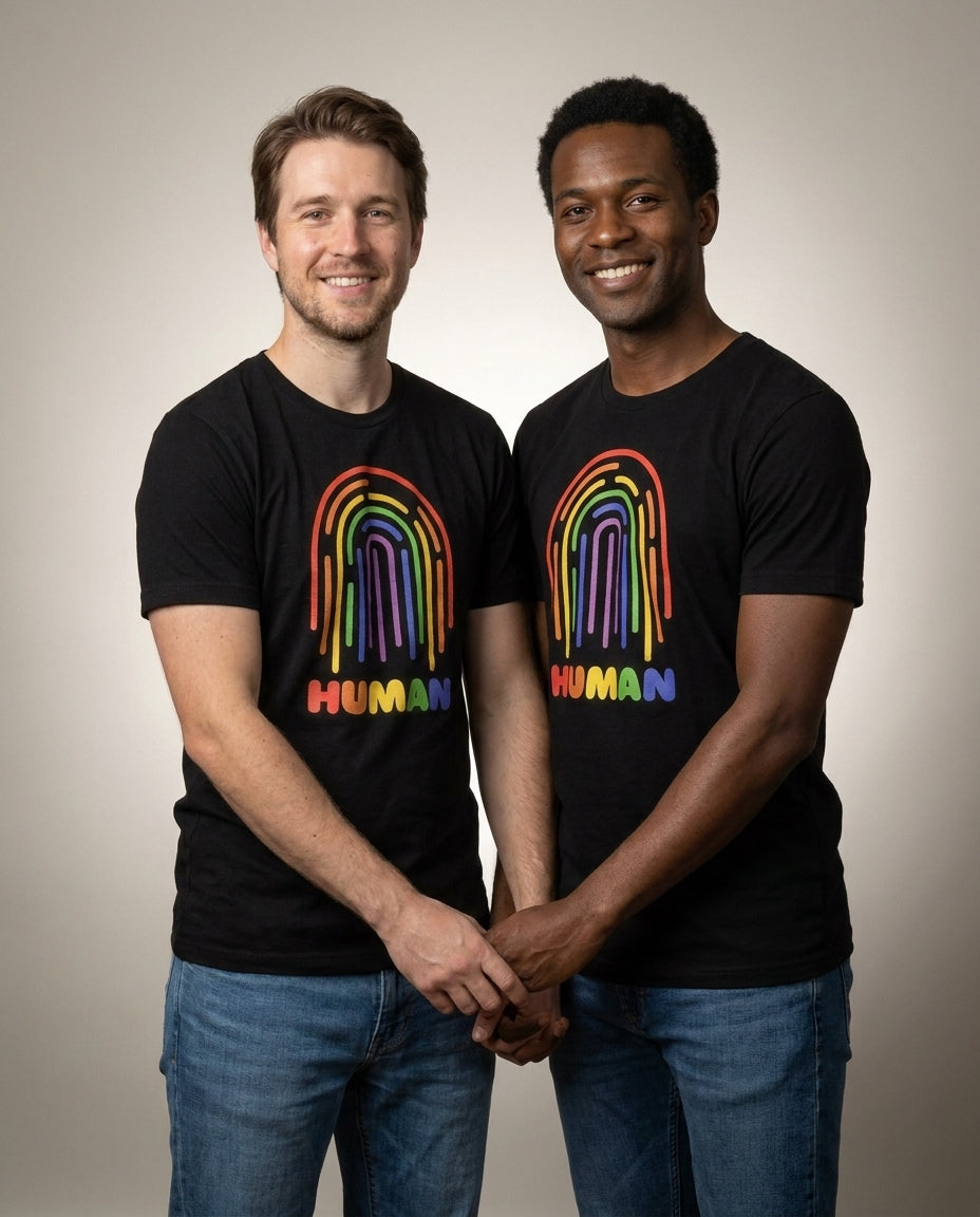 Two men holding hands in the HUMAN Pride tee