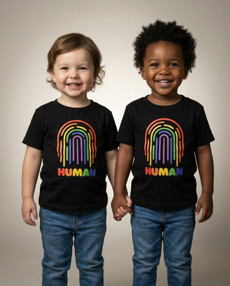 Two toddlers holding hands in the HUMAN Pride toddler tee