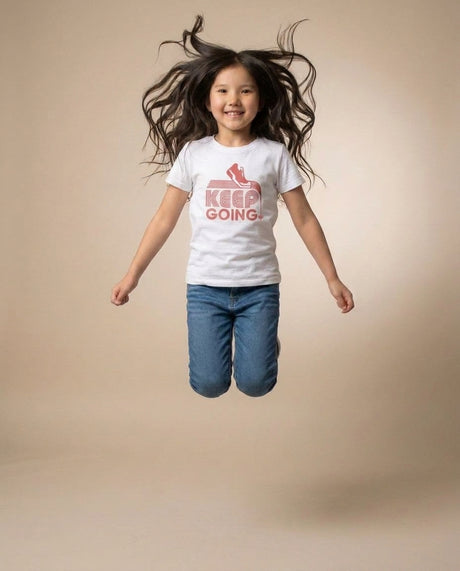 Youth jumping in Keep Going tee